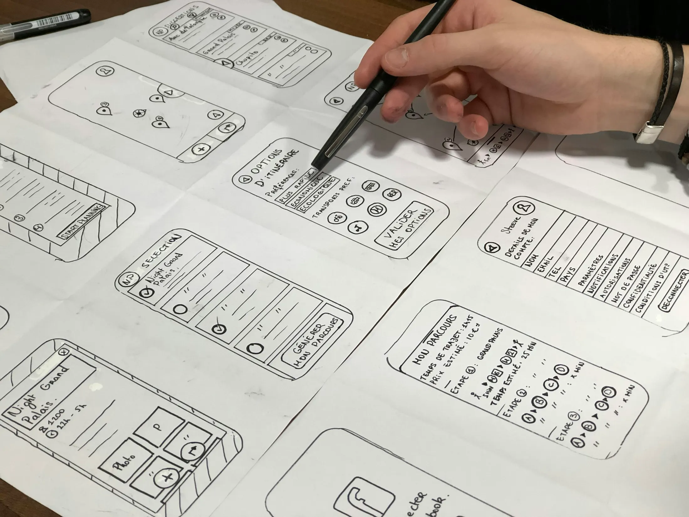 Hand sketching mobile app wireframe screens on paper during MVP prototyping